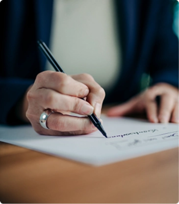 Persona firmando un contrato de inversión sobre un escritorio